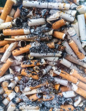 Şeffaf bir camın içinde sigara izmaritleri var. Seçici odak, camdan çekilen fotoğraf