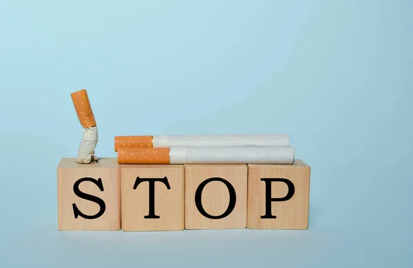 Stop smoking concept, cigarettes and STOP text on wooden blocks. World No Tobacco Day on May 31 concept. Selective focus