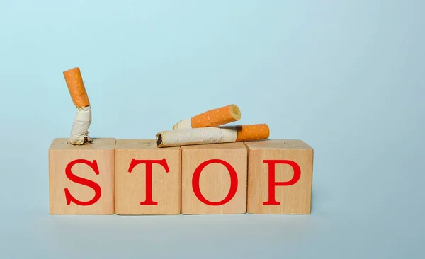 Stop smoking concept, cigarettes and STOP text on wooden blocks. World No Tobacco Day on May 31 concept. Selective focus