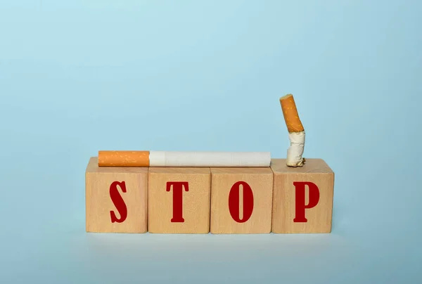 Stop smoking concept, cigarettes and STOP text on wooden blocks. World No Tobacco Day on May 31 concept. Selective focus