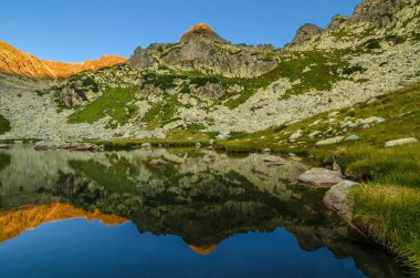 Romanya 'nın Karpat Dağları' ndaki Retezat Milli Parkı 'ndaki Taul Portii Gölü' nde güneş doğarken dağ manzarası ve buzul manzarası