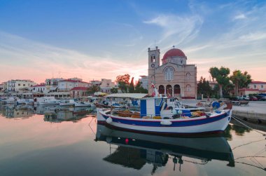 Yunanistan 'ın Saronik Körfezi' ndeki Aegina Adası 'na gün batımında demirlemiş yatları ve balıkçı tekneleri olan büyüleyici Aegina kasabasının limanı..