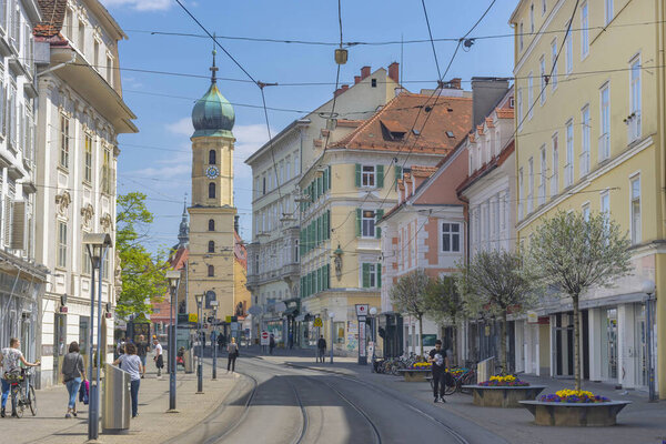Graz, Austria-April 25, 2021: beautiful street with shops in the old city center and the Franciscan Church in the background, in sunny spring day