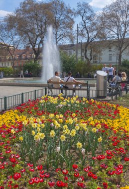 Graz, Avusturya-25 Nisan 2021: İnsanlar güneşli bir bahar gününde Avusturya 'nın Styria bölgesinin merkezindeki Jakominiplatz Meydanı' ndaki çeşmenin yanında dinleniyorlar..