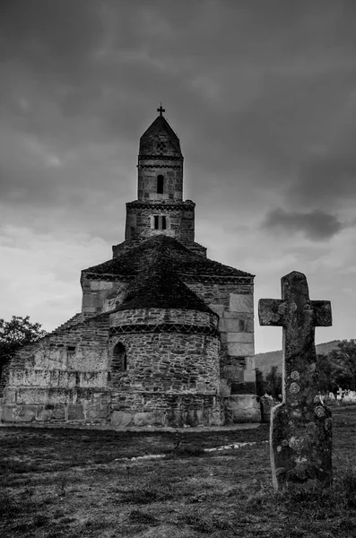 An old cross and Densus medieval church (Saint Nicholas), a Dacian and Roman temple in Hunedoara, Hateg, Romania