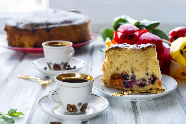 Pedazo de pastel con fruta y dos tazas de café — Foto de Stock