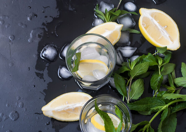 стаканы со льдом и лимоном, мятой и льдом на черном фоне
