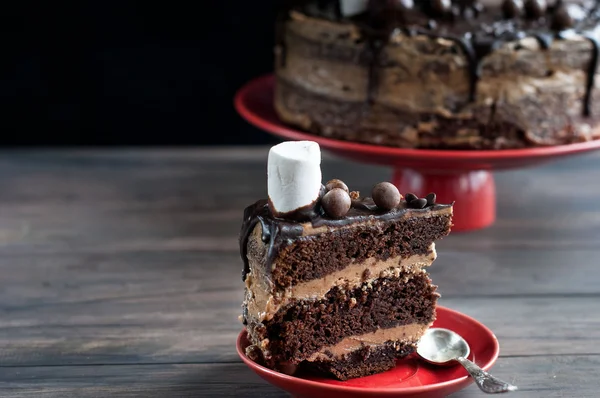 Kawałek ciasto czekoladowe i duży tort z polewy czekoladowe — Zdjęcie stockowe