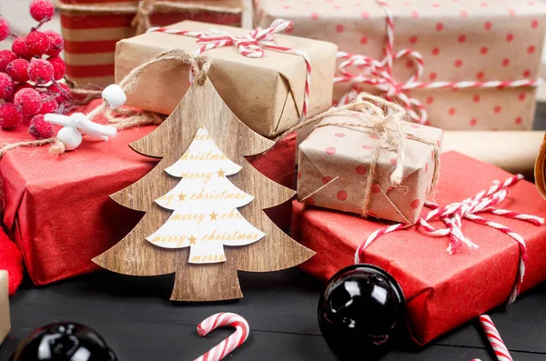 Crafted christmas handmade presents wrapped in craft paper, scrolls and xmas decoration on wooden background. Workplace for preparing new year decorations. Winter holidays concept.