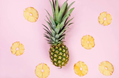 Pembe arka planda olgun sulu ananas ve etrafında kurumuş ananas parçaları. Meyve cipsi. Sağlıklı beslenme konsepti, atıştırmalık, şekersiz. Üst görünüm, alanı kopyala. .