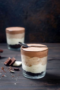 Koyu ahşap arka planda üç çikolatalı krema, seçici bir odak. Ev yapımı lezzetli, beyaz, sütlü ve koyu çikolatalı fırında tatlı yok.