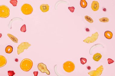 Pembe arka planda farklı meyve cipslerinin kurumuş dilimleri. Çeşitli meyveli cipsler. Sağlıklı beslenme konsepti, atıştırmalık, şekersiz. Üst görünüm, alanı kopyala. 