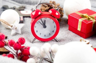 Kırmızı alarmlı Noel seti kırmızı ve beyaz bayram ahşap süslemeleri ve açık gri arka planda hediyelerle çevrili. Yeni yıl ya da kış arifesi kompozisyonu. Noel zamanı konsepti. Tebrik kartı,