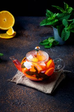 Portakal ve limon dilimli, böğürtlen, nane ve bal aromalı ev yapımı meyveli çay koyu kırsal arka planda. Sıcak sonbahar ya da kış içeceği. Çay demleme işlemi,