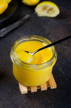 Koyu arka planda kaşıkla cam bir kavanozda ev yapımı limon dilimlenmiş taze limon. Boşluğu kopyala. 