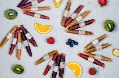 Gri arka planda çeşitli olgun meyveler ve kurutulmuş cipsler var. Meyve cipsi. Sağlıklı beslenme konsepti, atıştırmalık, şekersiz. Üst görünüm, alanı kopyala. 