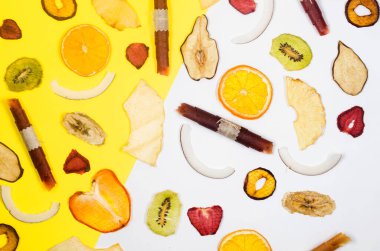 Kurumuş meyveler, beyaz ve sarı arka plana saçılmış cipsler. Meyve cipsi. Sağlıklı beslenme konsepti, atıştırmalık, şekersiz. Üst görünüm, alanı kopyala. 