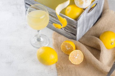 Cam şişede limoncello ve gri arka planda taze olgun sarı limonlar, geleneksel ev yapımı tatlı İtalyan limon likörü, güçlü alkollü içecek ve taze olgun limonlar..