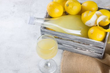 Limoncello in glass bottle and fresh ripe yellow lemons on the grey background, traditional homemade sweet Italian lemon liqueur, strong alcoholic drink and fresh ripe yellow lemons. clipart
