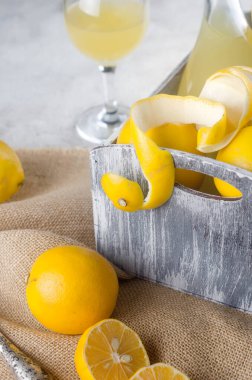 Cam şişede limoncello ve gri arka planda taze olgun sarı limonlar, geleneksel ev yapımı tatlı İtalyan limon likörü, güçlü alkollü içecek ve taze olgun limonlar..