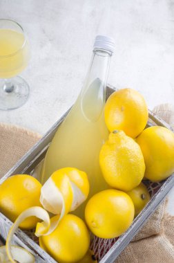 Cam şişede limoncello ve gri arka planda taze olgun sarı limonlar, geleneksel ev yapımı tatlı İtalyan limon likörü, güçlü alkollü içecek ve taze olgun limonlar..