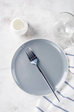 Zarif boş tabak, çatal bıçak takımı, sabah için bir fincan kahve, açık masa arka planı, üst manzara. Kahvaltı masası beyaz renkte ayarlanıyor.