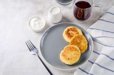 Krema, reçel ve bir fincan latte ile siyah tabakta süzme peynirli krep. Sağlıklı Kahvaltı. Ev yapımı yemek.