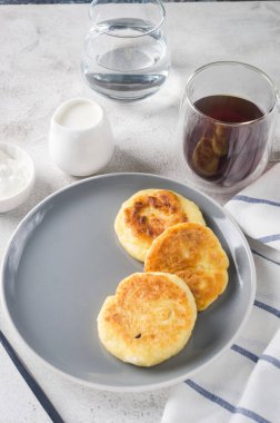 Krema, reçel ve bir fincan latte ile siyah tabakta süzme peynirli krep. Sağlıklı Kahvaltı. Ev yapımı yemek.