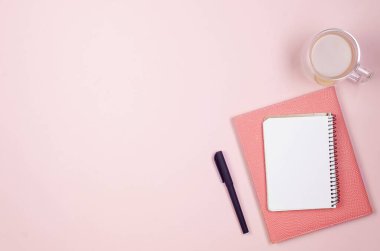 Düz uzanmış, ofis masası manzaralı. Çalışma masası boş, malzemeler, bardaklar ve kahve fincanları pembe arka planda. Asgari tarz ev ofisi ya da Modern Serbest İşyeri.