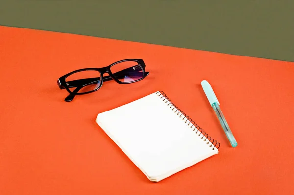 Бланширующая Белая Тетрадь Очки Ручка Оранжевом Зеленом Фоне Минималистская Концепция — стоковое фото