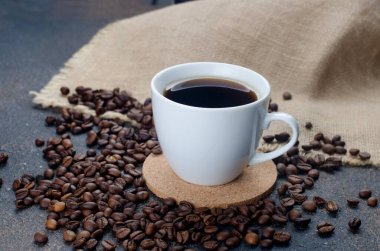 Koyu beton arka planda beyaz kahve ve kahve çekirdekleri. Sıcak içecekler, canlandırıcı bir kahvaltı..