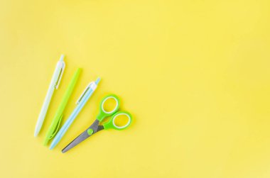 Okul konseptine geri dönelim. Sarı arka planda okul kırtasiyesi olan kalem kutusu. not defteri kağıdı, kalem, ataç ve kopyalama alanı olan yapışkan not, 