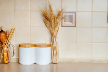 Tahta kapaklı mısır gevreği için kavanozlar, ahşap çatal bıçak takımı, kurutulmuş çiçekler ve mutfak masasındaki şişede sivri uçlar, İskandinav tarzı. Çevre dostu mutfak gereçleri ve dekorasyon, seçici odaklanma