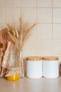Tahta kapaklı mısır gevreği için kavanozlar, ahşap çatal bıçak takımı, kurutulmuş çiçekler ve mutfak masasındaki şişede sivri uçlar, İskandinav tarzı. Çevre dostu mutfak gereçleri ve dekorasyon, seçici odaklanma