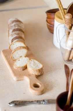 Dilimlenmiş Fransız Ekmeği. Kahvaltı için malzemeler, taze baget ve arka plandaki mutfak aletlerinde domates, İskandinav tarzı. Seçici odak