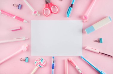 Okul konseptine geri dönelim. Pembe arka planda okul kırtasiyesi olan kalem kutusu. Boş defter kağıdı, kalem, ataç ve kopya alanı olan yapışkan not, düz konum.