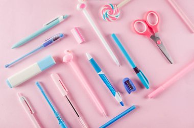 Okul konseptine geri dönelim. Pembe arka planda okul kırtasiyesi olan kalem kutusu. Boş defter kağıdı, kalem, ataç ve kopya alanı olan yapışkan not, düz konum