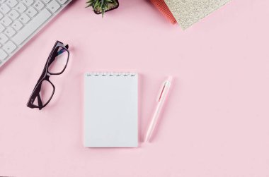 Okul konseptine geri dönelim. Pembe arka planda okul kırtasiyesi olan kalem kutusu. Klavye, defter kâğıdı, kalem, ataç ve kopya alanı olan yapışkan not, düz konum