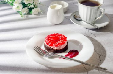 Çikolatalı mini pasta, berri marshmallow ve jöle tabakta ve açık gri arka planda cam bardakta bir fincan kahve, üst manzara. Lezzetli tatlı. Kahvaltı masası kurulumu. 