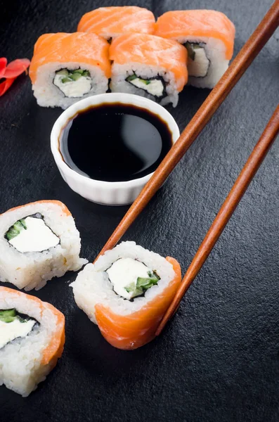 费城的木制筷子 寿司卷与鲑鱼 奶油奶酪和酱汁的黑色背景 日本菜 寿司菜单 — 图库照片