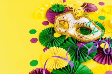 Renkli kağıt konfetileri, karnaval maskesi ve sarı arka planda fotokopi alanı, tebrik kartı ve karnaval ya da doğum günü için parti davetiye şablonu tasarımı, Mardi Gras,