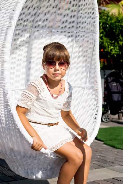 Девочка в очках в раскачивающемся кресле в солнечный день — стоковое фото