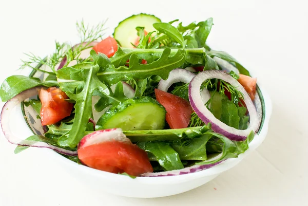 Салат смесь руколли, помидоров, огурцов с кольцами красного цвета на — стоковое фото