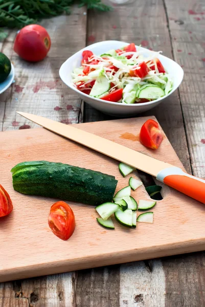 Komkommer en tomaat segmenten op een snijplank — Stockfoto