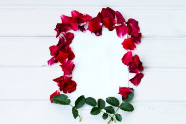 card with leaves and rose petals on the wooden background