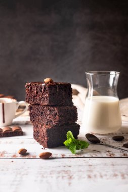 Eritilmiş çikolata soslu çikolatalı kek, badem ve masada bir bardak sütle naneli yaprak. Fırın, şekerleme konsepti