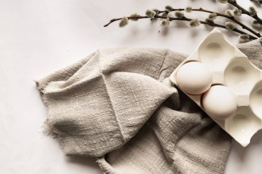 Paskalya sofrası, boş beyaz seramik tabak, çatal bıçak takımı ve beyaz masada söğüt dalları. Tarafsız renkler. Paskalya arkaplanı.