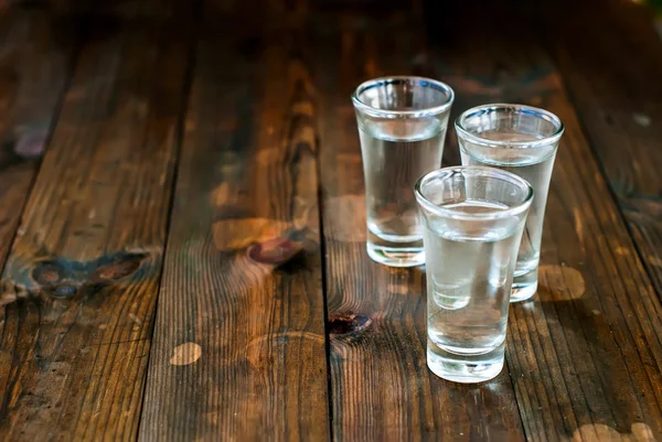 Vodka fria em um copo em uma mesa de madeira — Fotografia de Stock