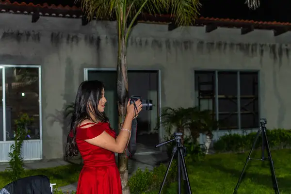 プロのカメラで写真を撮る赤いドレスを着た若い女性 — ストック写真