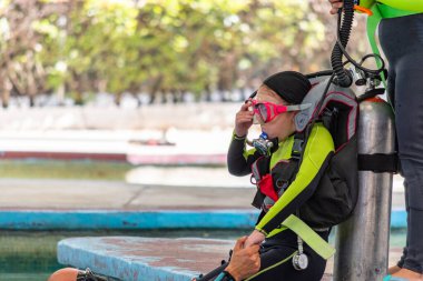 Dalış sınıfındaki kız suya girmeden önce gözlüklerini ayarlıyor.